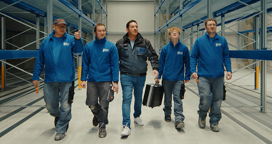 Das Team von Gtech geht in einer Lagerhalle zu einem Projekt